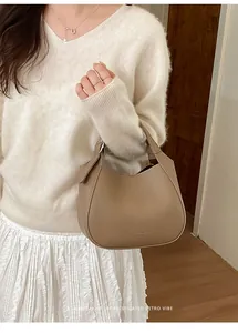 Gros plan du sac seau en cuir kaki avec une tenue minimaliste et sophistiquée