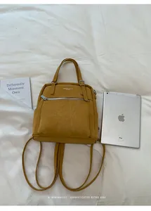 Detailansicht eines gelben Mini-Rucksacks auf weißem Stoff mit iPad-Vergleich