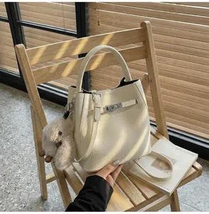 Dettaglio della borsa a secchiello in pelle crema con chiusura in metallo e ciondolo a coniglio