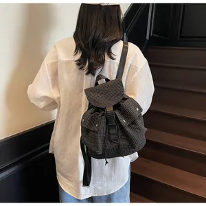 Detail of checkered backpack featuring flap buckle closure and adjustable side pockets