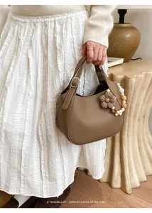 Détail d'un sac seau en cuir grainé marron souple avec un charme de fleur tissée