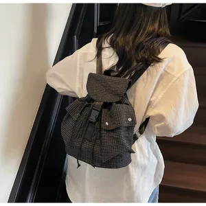Detail of grey plaid backpack with brown trim and secure black buckle closure