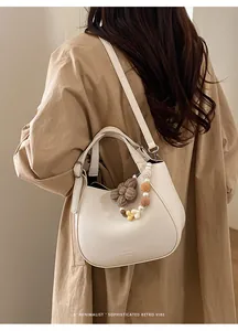 Détail d'un sac seau crème minimaliste avec des charms fleuris et perles élégantes