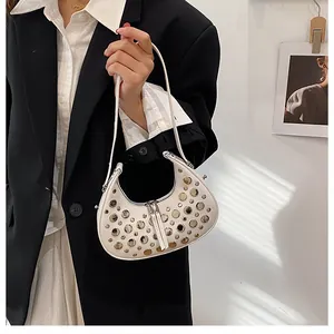 Detail of off-white leather crescent bag with mixed metal studs on an underarm bag