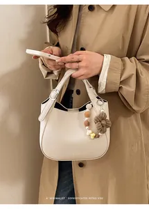 Détail du sac hobo en cuir blanc cassé avec breloque fleur tricotée et perles colorées