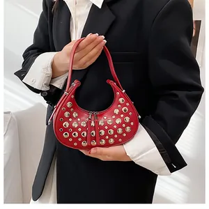 Detail of red crescent shoulder bag with golden studs on black suit background