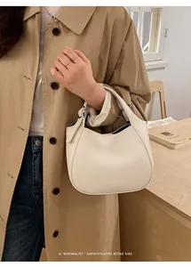 Détail de la texture en cuir crème du sac seau minimaliste et des surpiqûres de haute qualité