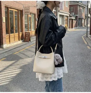 Dettaglio borsa a secchiello in pelle beige con fibbia in metallo e ciondolo a coniglio