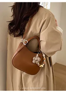 Sac seau en cuir marron avec breloque florale dans un style rétro minimaliste