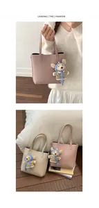 Détail de sacs seaux en cuir grainé rose et beige avec des breloques d'ours mignonnes