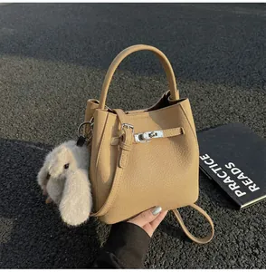 Dettaglio borsa a secchiello in pelle beige con grana e ciondolo a forma di coniglio