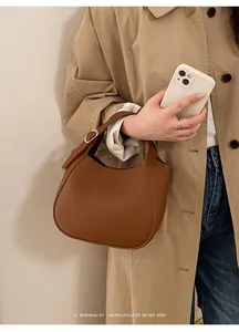 Détail d'un sac seau en cuir marron caramel avec logo embossé et boucle en métal argenté