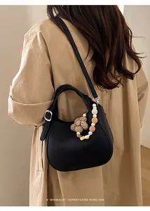 Détail du sac seau en cuir grainé noir avec breloque perle et boucle métallique argent