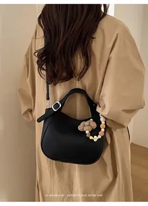 Détail du sac seau en cuir noir avec breloques perles fleuries et bandoulière chaîne