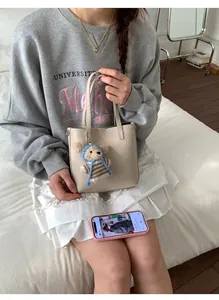 Détail du sac seau en cuir beige avec un charmant pendentif ours en crochet sur le devant