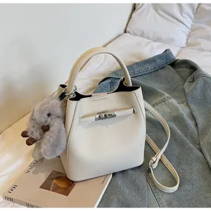 Dettaglio della borsa a secchiello in pelle bianco crema con ciondolo a coniglio