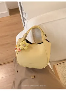 Détail du sac seau en cuir grainé jaune avec breloque fleur et boucle en métal argent