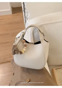 Détail d'un sac seau en cuir grainé crème avec logo et breloque fleurie