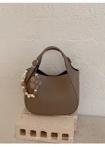 Détail du sac seau en cuir grainé marron avec perles et chaîne décorative florale