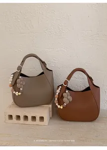Détails de sacs seau en cuir souple taupe et caramel avec pendentifs floraux