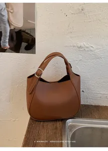 Vue détaillée du sac seau en cuir grainé marron sur une surface en bois minimaliste