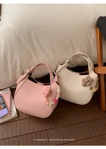 Détail des sacs seaux en cuir rose et beige avec pendentifs cœur et fleurs