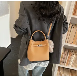 Borsa a secchiello in pelle marrone con fibbia in metallo indossata a tracolla da una modella