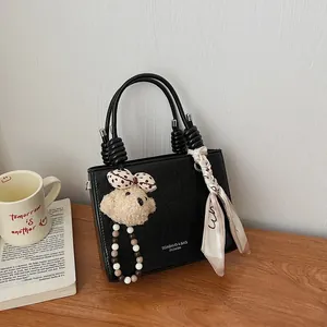 Elegante borsa a mano nera con manico a spirale, ciondolo a orsetto e foulard di seta
