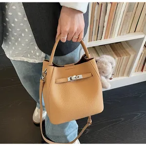 Dettaglio borsa a secchiello in pelle color cammello con fibbia argento e charm morbido
