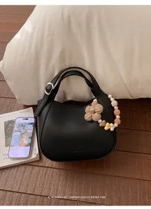 Détail du sac seau noir en cuir grainé avec breloques décoratives en perles et fleurs
