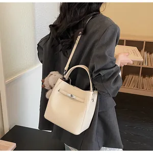 Dettaglio borsa beige in pelle martellata con fibbia in metallo e ciondolo orsetto