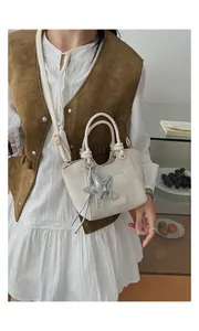 Detail of cream bucket bag with silver starfish charm and textured canvas fabric finish