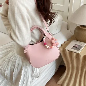 Sac seau en cuir grainé rose avec breloque fleurie présenté dans un décor de maison