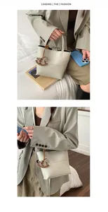 Détail d'un sac seau en cuir blanc cassé avec pendentif cheval sur blazer olive