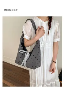 Detail of grey canvas tote bag featuring black polka dots and a white lace bow decoration