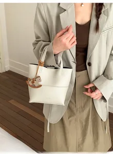 Détail du sac seau blanc motif litchi avec breloque cheval en bois et logo de marque