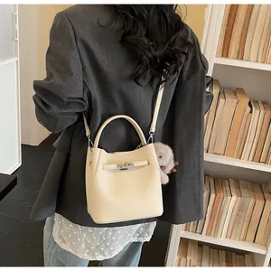 Dettaglio della borsa in pelle bianco crema con fibbie argentate e ciondolo di peluche