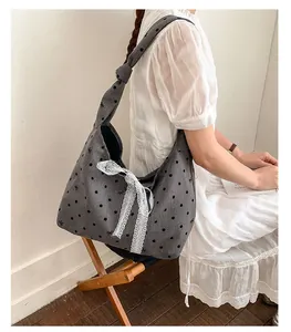 Detail of grey canvas tote bag with black polka dots and white lace bow decoration