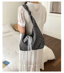 Detail of grey polka dot canvas tote featuring a large white lace bow and knotted strap