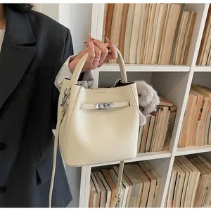 Dettaglio della borsa a secchiello bianco crema con pelle martellata e ciondolo peluche