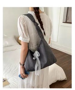 Detail of dark grey polka dot canvas tote bag featuring a knotted strap and lace bow