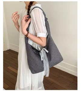 Close-up of gray canvas tote bag with black polka dots and white lace bow detail