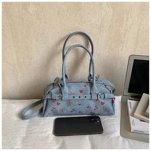 Detail of blue floral denim boston bag with adjustable strap and retro metal buckle