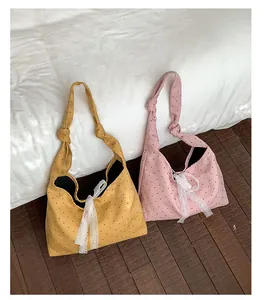 Detail of polka dot canvas tote bags in ginger and pink with white lace bows