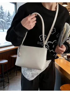 Chic cream leather bucket bag detail with silver chain charm shown in a cozy cafe setting