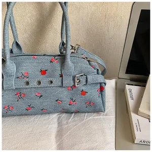 Close-up of light blue floral denim tote bag with silver hardware and zipper details