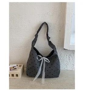 Detail of grey canvas tote bag featuring white lace bow and black polka dot pattern