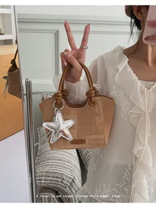 Detail of vintage textured bucket bag with silver star charm and knotted handle
