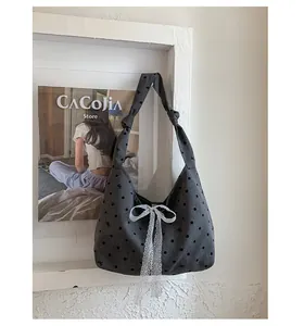 Detail of grey polka dot canvas tote with lace bow and knotted shoulder strap