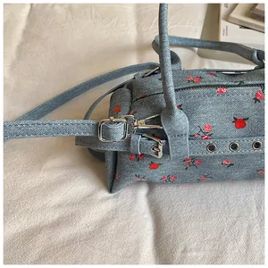 Detail of blue denim texture lunch bag with red floral patterns and silver hardware